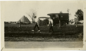 Two men walk past a Red Cross truck after a tornado in Castle Rock, Minnesota on May 20, 1920. The truck may or may not have been associated with the Northfield Red Cross chapter.
